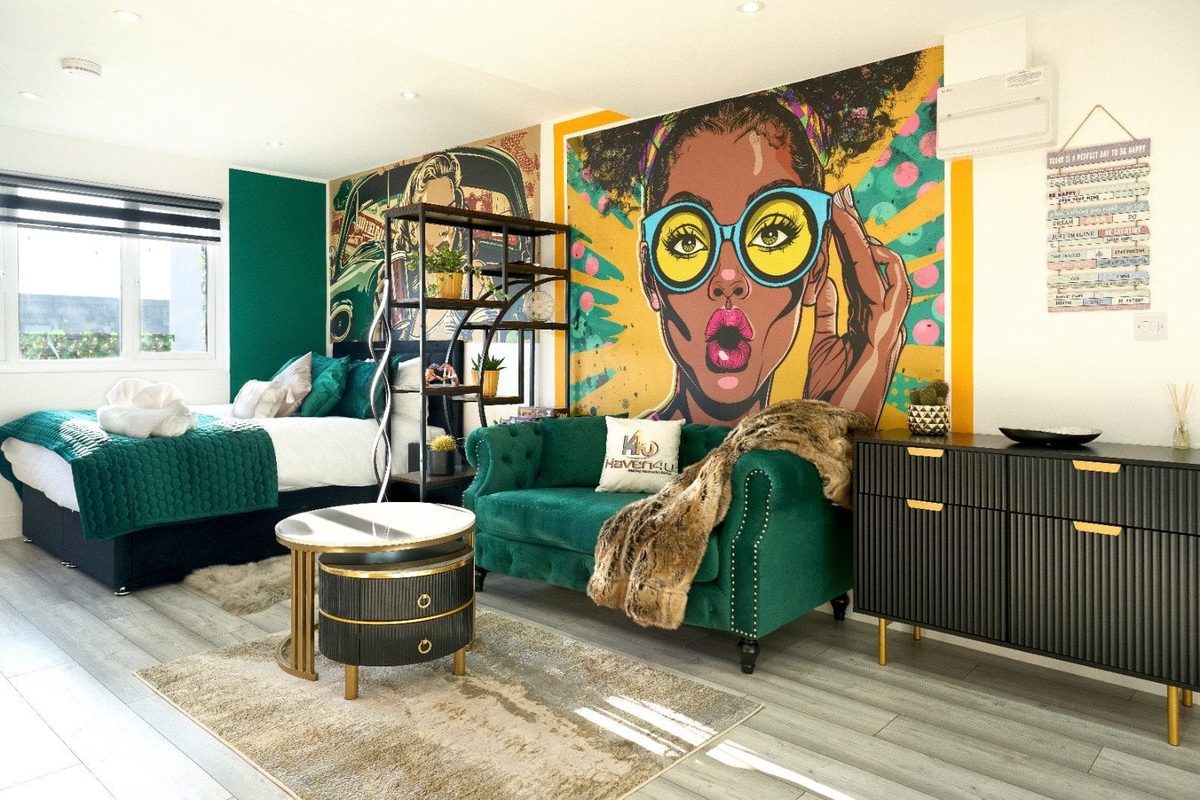 Open-plan room with a green velvet sofa and a comic-strip mural